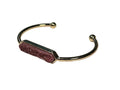 Gold bracelet with a pink gemstone on a light white background