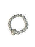 Beaded bracelet with white and gray beads on a light gray background