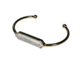 Gold bracelet with a central stone on a white background