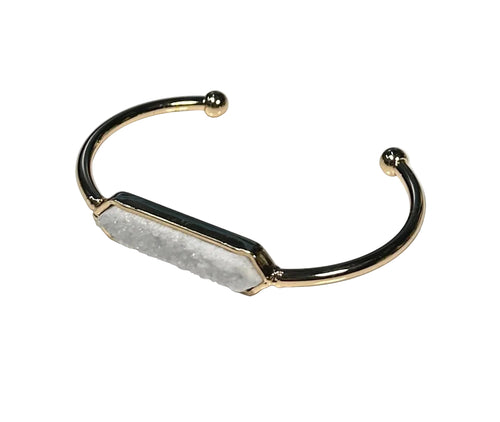 Gold bracelet with a central stone on a white background